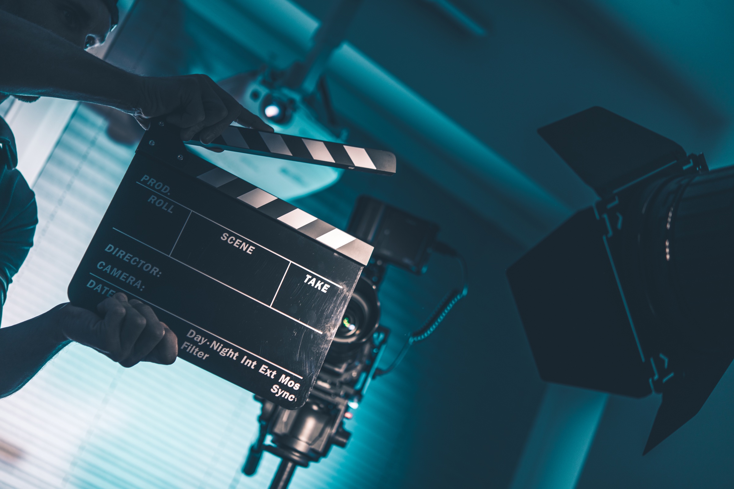 Filmmaker holding a clapperboard on a lit film set